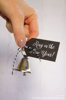 a hand holding a small bell with a tag that says ring in the new year