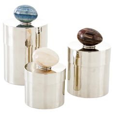 three metal containers with marbles on top of them