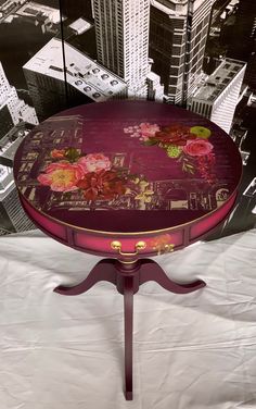 a table with flowers painted on it in the middle of a cityscape background