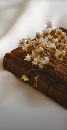 white flowers are placed on top of an old book that is laying on the bed