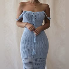 a woman wearing a blue crochet dress with an off the shoulder neckline