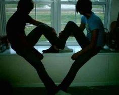 two people sitting on a window sill in the dark