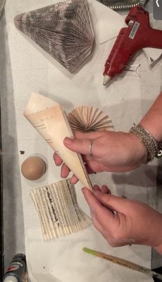 two hands are working on an object with wood shavings and other crafting supplies