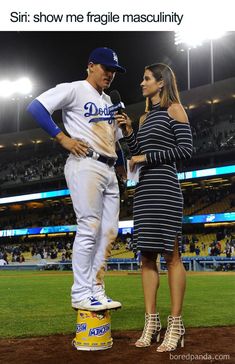 a woman standing next to a man on top of a baseball field