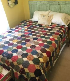 a bed with a colorful quilt on top of it next to a night stand and lamp