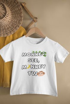 a t - shirt that says monkey see, monkey two on it next to a straw hat