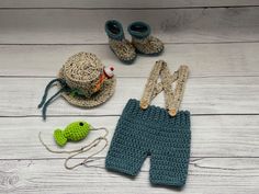 a crocheted baby outfit, hat and booties on a white wooden floor