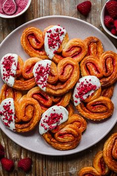 a white plate topped with pastries covered in icing next to raspberries