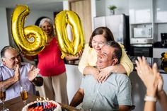 an older couple celebrating their 60th birthday with gold balloons and candles in the shape of the number sixty