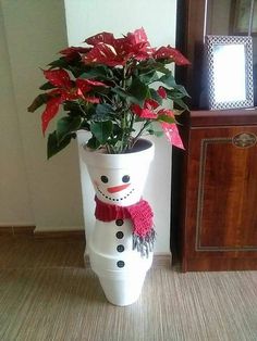 a snowman planter with poinsettis in it on the floor next to a mirror