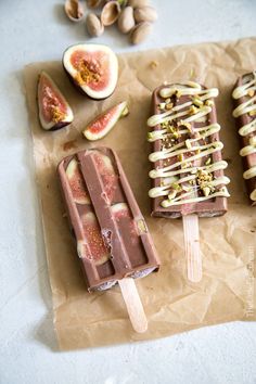 three popsicles with different toppings sitting on top of wax paper next to figs