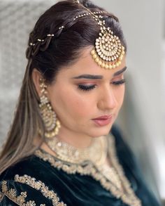 a woman with long hair wearing a head piece and jewelry on her face, looking down