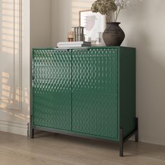 a green cabinet sitting next to a vase with flowers