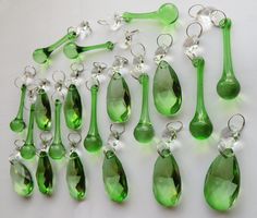 a group of green and white glass spoons hanging from hooks on a counter top