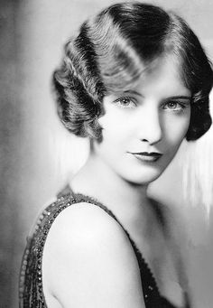 an old black and white photo of a woman with her hair up in a bun