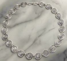 This handmade sterling silver jewelry necklace features the traditional Greek Spiral Motif a symbol of infinity of constant motion endlessness cut out around the entire necklace. Sterling Silver Jewelry the brightest of all precious metals Special design of the clasp so that your jewelry remains at all times at its place Handcrafted necklace. Forget the standardized jewelry on the market! Stand out with our individually handmade ELEFTHERIOU EL Jewelry Inspired by Ancient Greece Jewelry Made in G Ancient Greece Jewelry, Greece Jewelry, Greek Necklace, Spiral Necklace, Silver Jewelry Necklace, Handcrafted Necklace, Ancient Greece, Necklace Sterling Silver, Handmade Sterling Silver