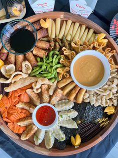 a platter filled with different types of snacks and dipping sauces on top of it