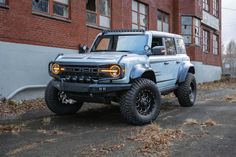 a light blue truck parked in front of a brick building on the side of a road