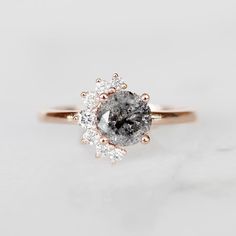 a close up view of a diamond ring on a marble surface with the center stone surrounded by three smaller diamonds