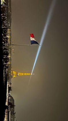 an airplane flying in the sky over a tall building with lights on it's side