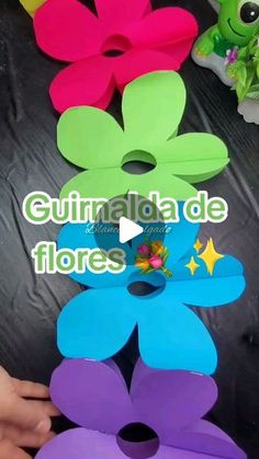 several different colored flower shaped boxes on a table with one being held up by someone's hand