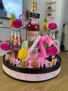 a pink flamingo themed birthday cake with pineapples and liquor bottles in the background