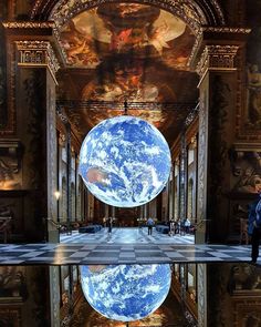 a reflection of the earth in a pool of water at an art museum with people standing around it