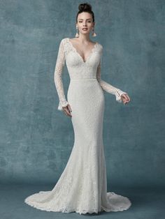 a woman in a white wedding dress with long sleeves and an open back, standing against a