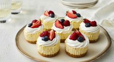 cupcakes with white frosting and fresh berries on top are arranged on a plate