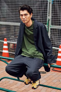 a young man is sitting on a rail in front of traffic cones and wearing glasses