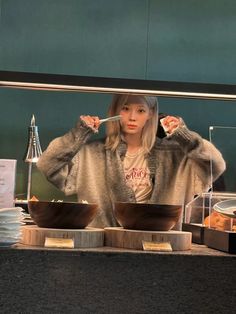 a woman standing behind a counter holding a spoon in her hand while eating food from bowls