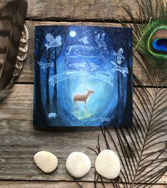 a painting on a wooden table with rocks, feathers and an animal in the background