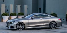 a silver mercedes benz coupe parked in front of a building with potted planters