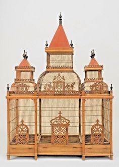 an ornate birdcage with red roof and two smaller birds in it's cage