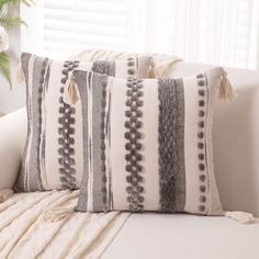 a white couch with two pillows on top of it next to a plant and window