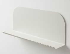 a white wall mounted shelf on the side of a wall