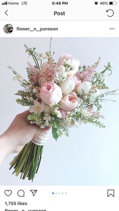 a person holding a bouquet of flowers in their hand with white and pink flowers on it