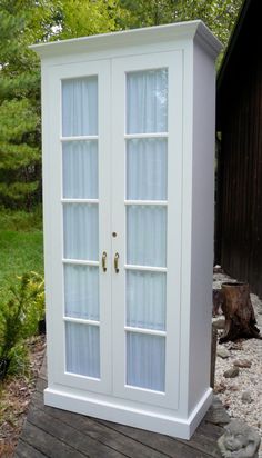 a white cabinet sitting on top of a wooden deck