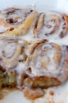 cinnamon rolls with icing sitting on top of a white plate