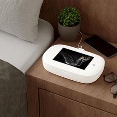 an electronic device sitting on top of a wooden table next to a phone and glasses