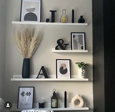 some white shelves with pictures and plants on them