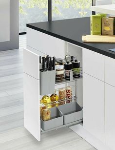 an open cabinet in the middle of a kitchen with lots of bottles and containers on it