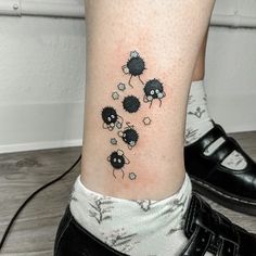 a small black and white sheep tattoo on the right side of the leg, with three smaller ones running behind it