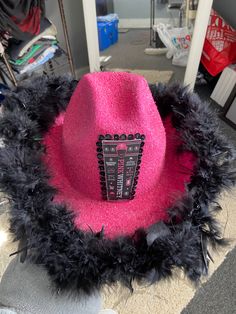 a pink hat with black feathers and a cell phone on it's front side