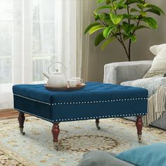 a blue ottoman sitting on top of a rug in front of a couch and coffee table