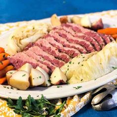 corned beef, potatoes and carrots on a white plate with a fork next to it