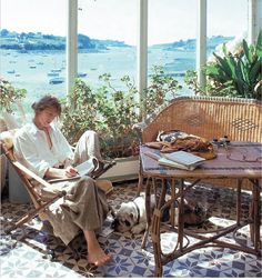 a woman sitting in a wicker chair next to a table with a dog on it