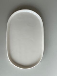 an empty white plate sitting on top of a gray tableclothed floor with no one around it