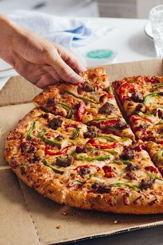 a person taking a slice of pizza from a box