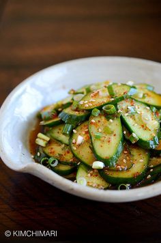 a white bowl filled with sliced cucumbers and sauce